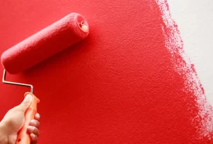 Pessoa pintando parede sem erros usando rolo em ambiente interno.