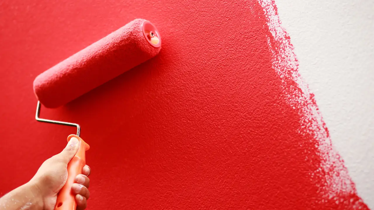 Pessoa pintando parede sem erros usando rolo em ambiente interno.