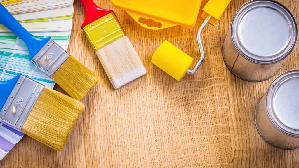 Conjunto de ferramentas para pintar paredes, incluindo rolo, pincel e tinta.