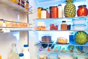 Geladeira bem organizada com alimentos frescos em potes herméticos e organizadores transparentes.