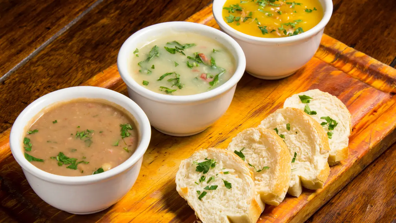 Caldos quentes em canecas de cerâmica, com diversos sabores, para uma festa junina organizada.