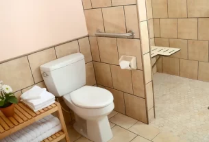 Banheiro moderno e seguro, com um piso antiderrapante no box e barras de apoio na parede, garantindo a prevenção de quedas.