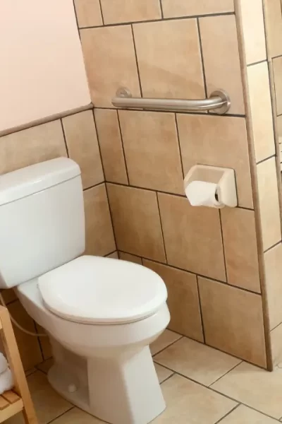 Banheiro moderno e seguro, com um piso antiderrapante no box e barras de apoio na parede, garantindo a prevenção de quedas.