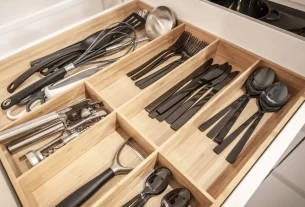Close-up de uma gaveta de cozinha com um organizador de talheres de bambu perfeitamente arrumado.