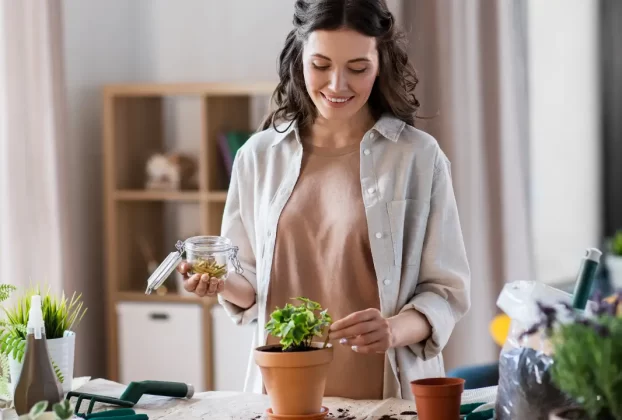 Mulher sorrindo ao adicionar adubo com biorresíduos urbanos em um vaso de planta.